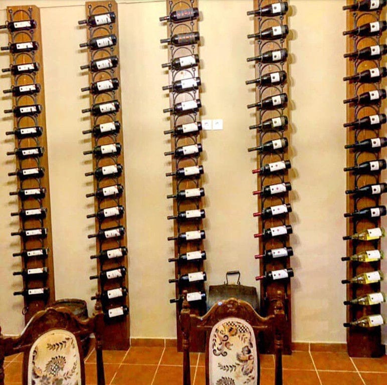 wine bottles in horizontal position into wood supports on the wall at Klima Grampsa
